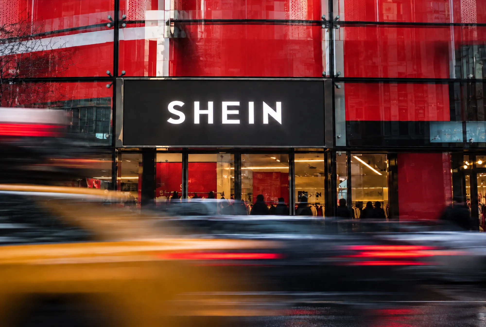 A SHEIN storefront at dusk, traffic streaming past
